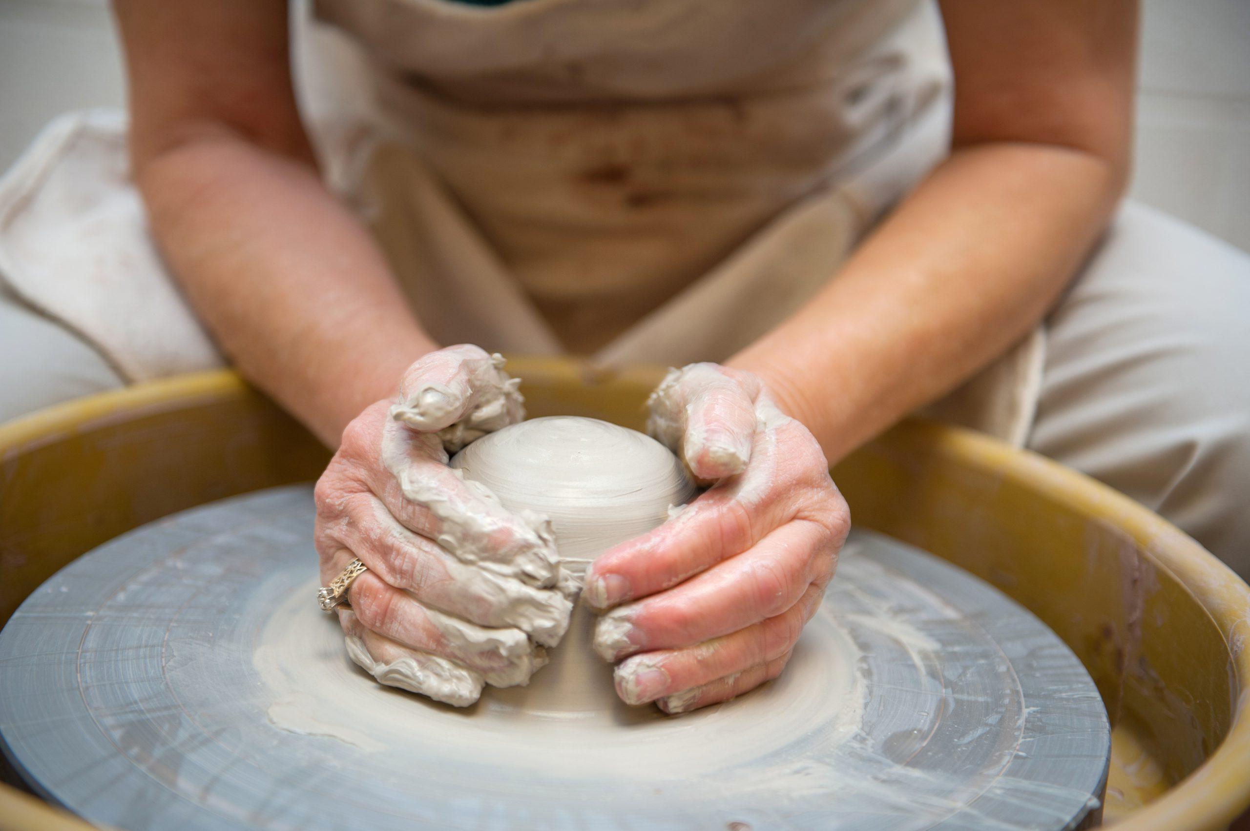 A person using a potter's wheel to create something with clay.