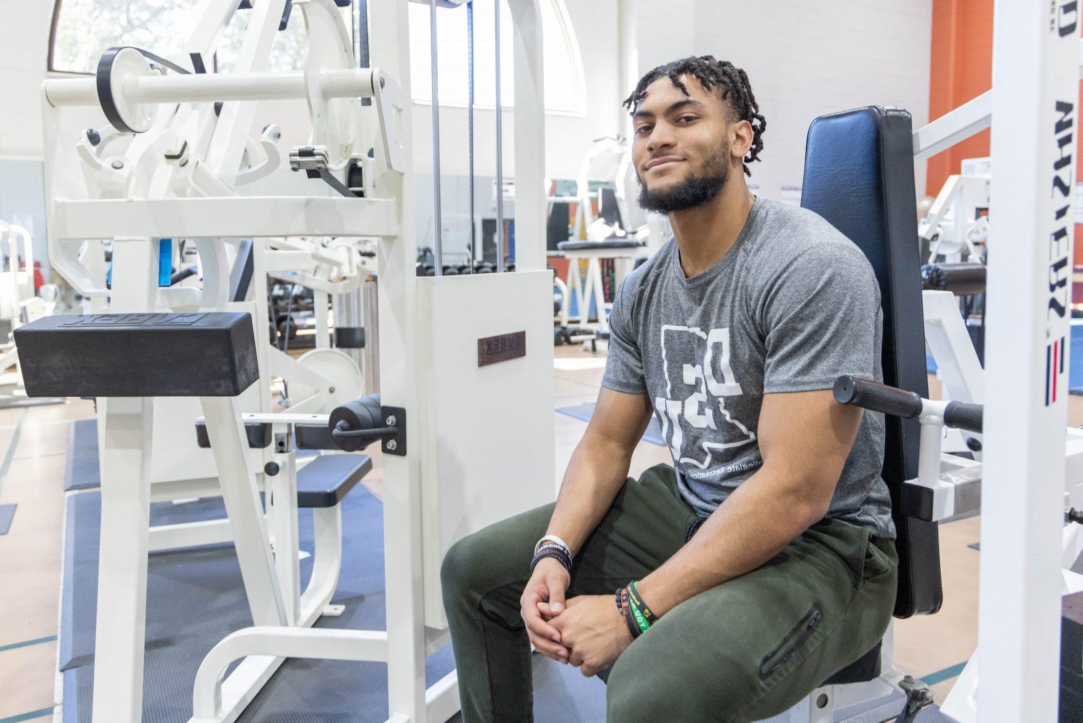 A man sitting on an exercise machine in a fitness center.