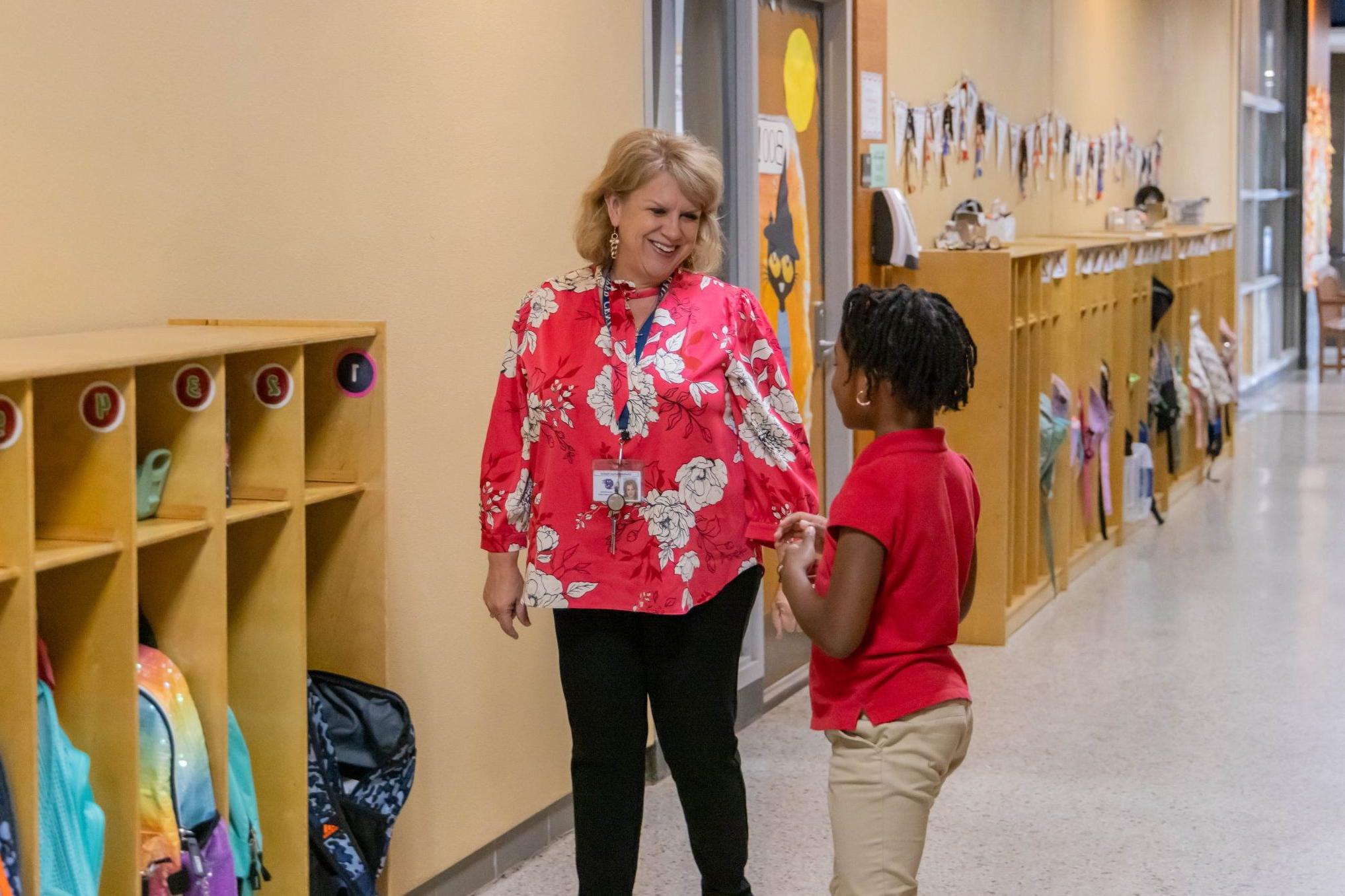 School administrator giving an elementary student a high-five in the hallway.